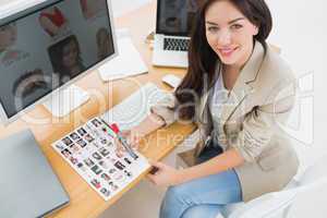 Female artist sitting at desk with computers in office