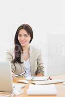 Well dressed woman with laptop at desk in office