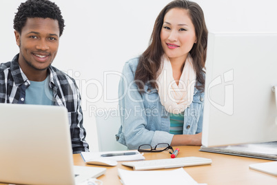 Casual couple using computers in office