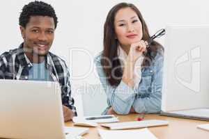 Casual business couple using computers in office