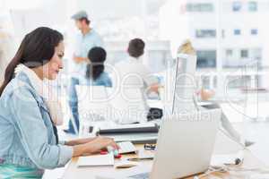 Woman using computer with colleagues behind in office