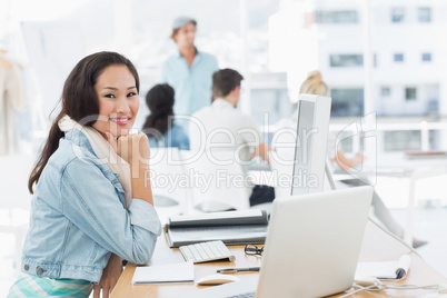 Casual young woman with colleagues behind in office