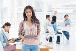 Artist holding digital tablet with colleagues in background at o