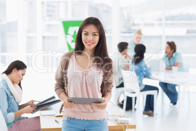 Artist holding digital tablet with colleagues in background at o