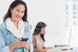Smiling young woman text messaging in office