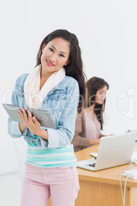 Casual artist using digital tablet with colleague in background