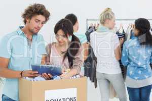 People with clothes donation while using digital tablet