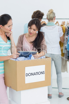 People with clothes donation while using digital tablet