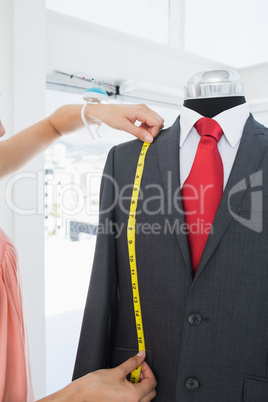 Extreme close-up of hands measuring suit on dummy