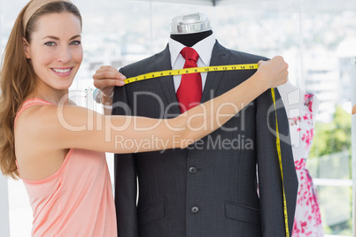 Female fashion designer measuring suit on dummy