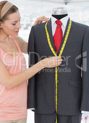 Female fashion designer measuring suit on dummy