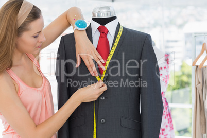 Female fashion designer measuring suit on dummy