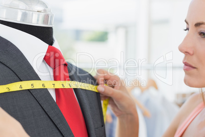 Close-up of a female fashion designer measuring suit on dummy