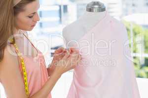 Beautiful female fashion designer working on pink fabric