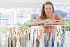 Female fashion designer with rack of clothes in store