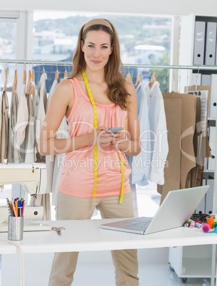 Female fashion designer with laptop and cellphone in studio