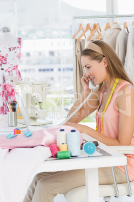 Young female fashion designer using phone