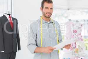 Male fashion designer holding sketch in the studio