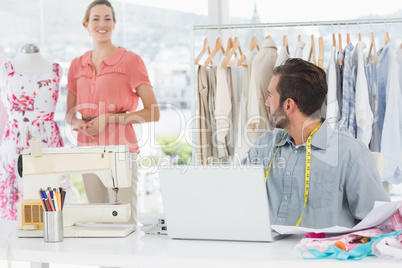 Man using laptop with fashion designer working at studio