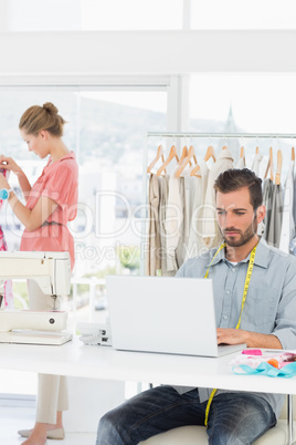 Man using laptop with fashion designer working at the studio
