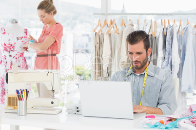 Man using laptop with fashion designer working at studio