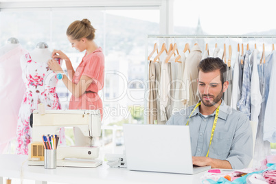 Man using laptop with fashion designer working at studio
