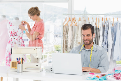 Man using laptop with fashion designer working at studio