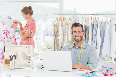 Man using laptop with fashion designer working at studio