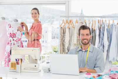 Man using laptop with fashion designer working at studio