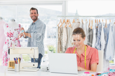 Woman using laptop with fashion designer working at studio