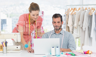 Fashion designers using laptop in bright studio
