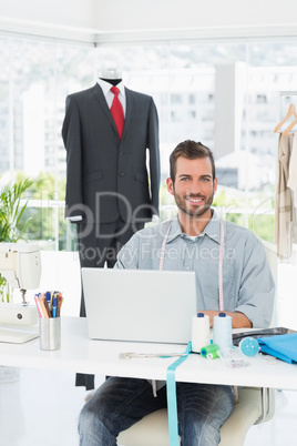 Smiling male fashion designer using laptop in studio