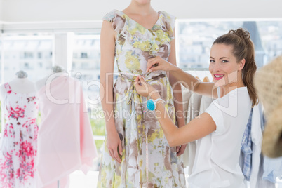 Female fashion designer measuring model's waist