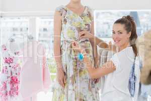 Female fashion designer measuring model's waist
