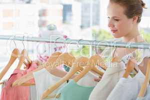 Smiling female customer at clothing rack in store