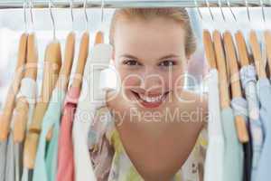 Happy female customer amid clothes rack