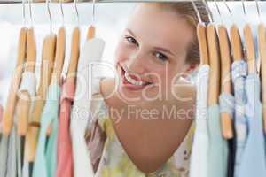 Happy female customer amid clothes rack