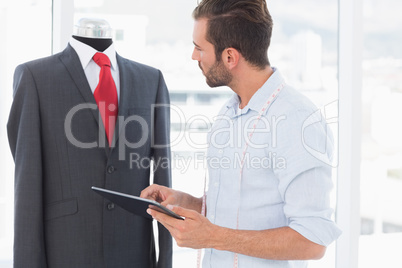 Concentrated fashion designer with digital tablet looking at sui