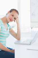 Smiling young casual woman in front of laptop at office