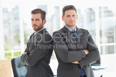 Businessmen standing with arms crossed in office