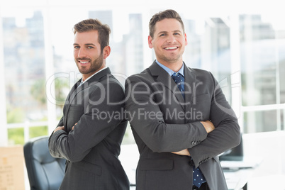 Businessmen standing with arms crossed in office