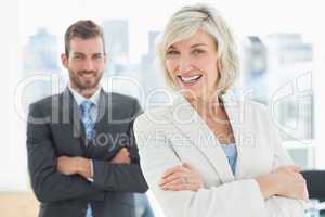 Mature businesswoman and young man with arms crossed