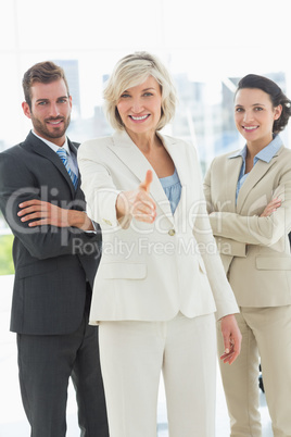 Confident businesswoman offering handshake with team in office