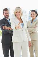 Confident businesswoman offering handshake with team in office