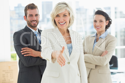 Confident businesswoman offering handshake with team