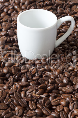 einzelne espressotasse steht zwischen kaffeebohnen