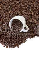 kaffeetasse liegt zwischen vielen kaffeebohnen