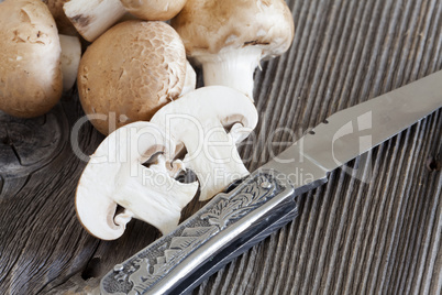 taschenmesser und champignons auf holzbrett