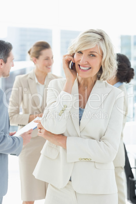 Mature businesswoman on call with colleagues discussing at offic