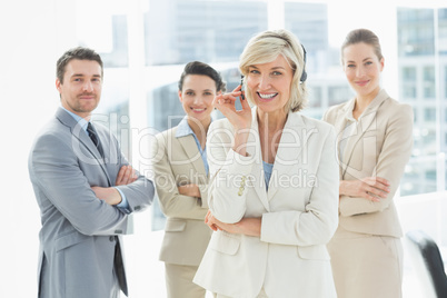 Mature businesswoman wearing headset with colleagues in office